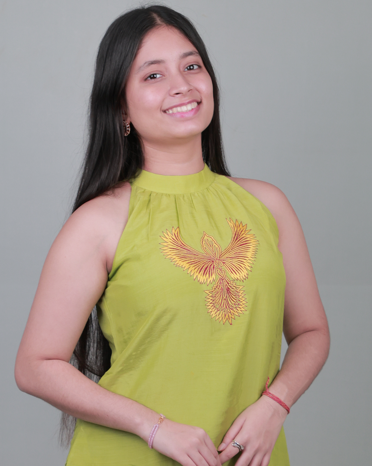 Woman wearing a green sleeveless top with a floral design on a gray background